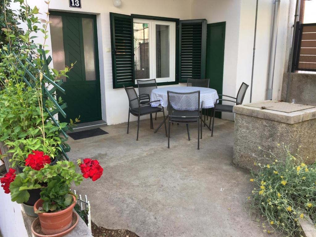 a table and chairs on a patio with red flowers at Holiday Home Olea in Punat