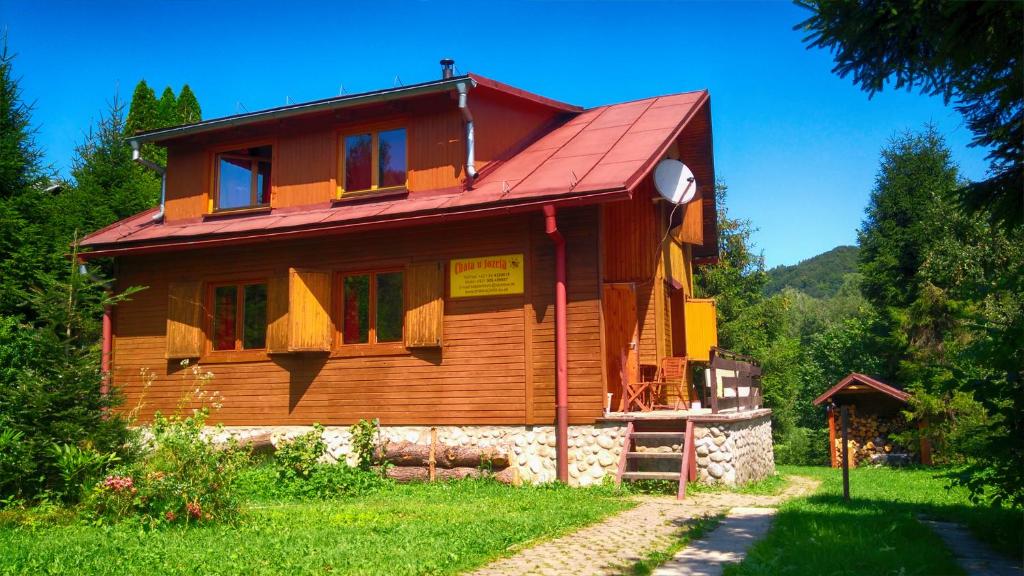 Chata U Jozefa في Malý Lipník: منزل خشبي بسقف احمر