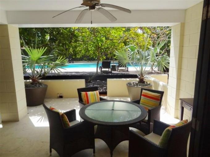 a patio with a table and chairs and a pool at Brownes Condominium 2 in Bridgetown