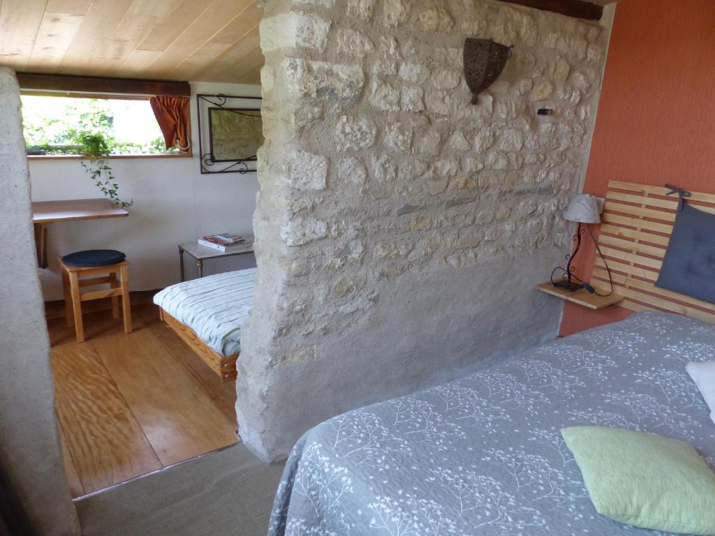 a bedroom with two beds and a stone wall at La Maison Rouge in Chauvigny