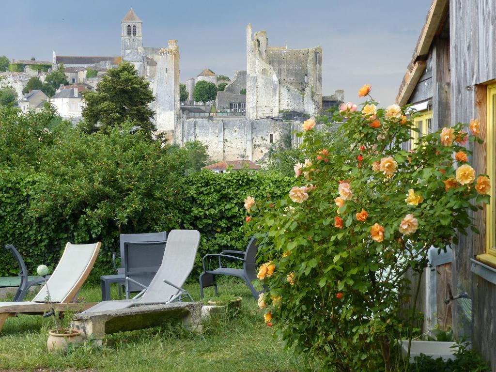 um grupo de cadeiras e um arbusto com flores em La Maison Rouge em Chauvigny