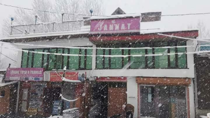 a building with snow falling on it in a city at Hotel Jannat in Srinagar
