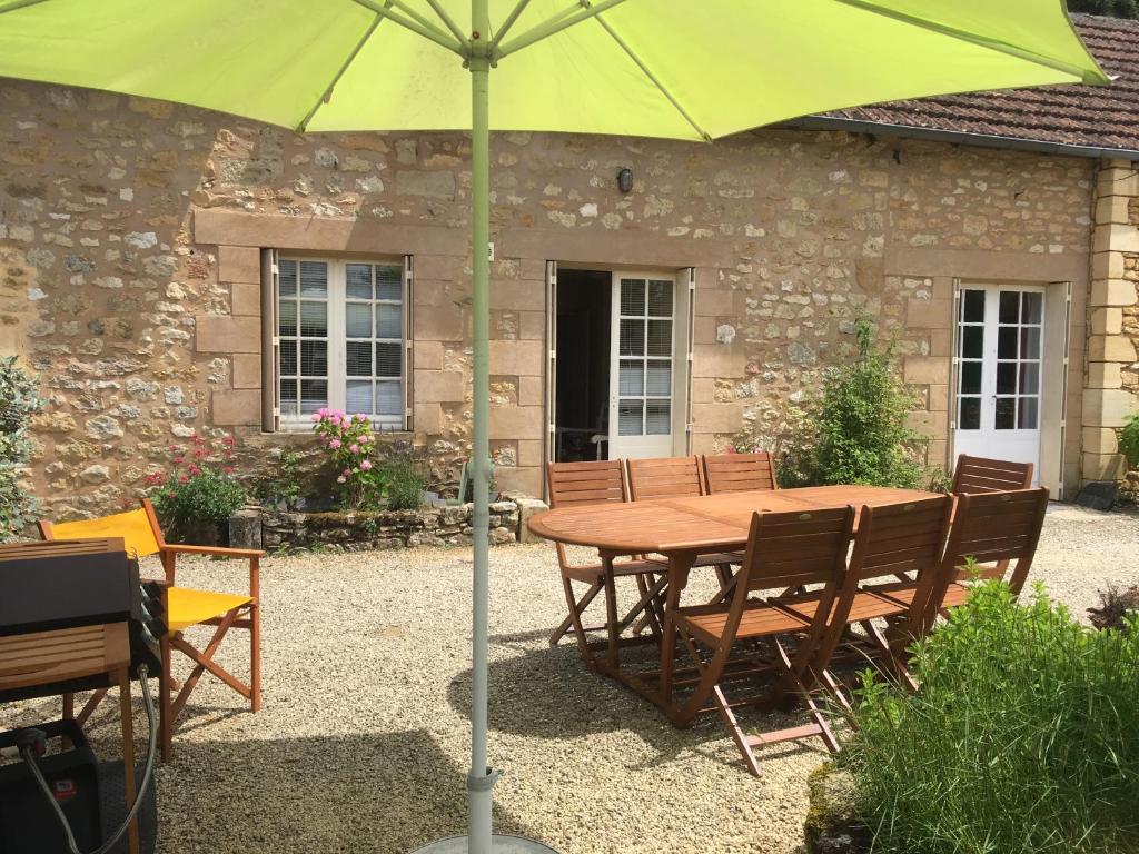 une table et des chaises en bois avec un parasol vert dans l'établissement Le Cuvier, à Sarlat-la-Canéda