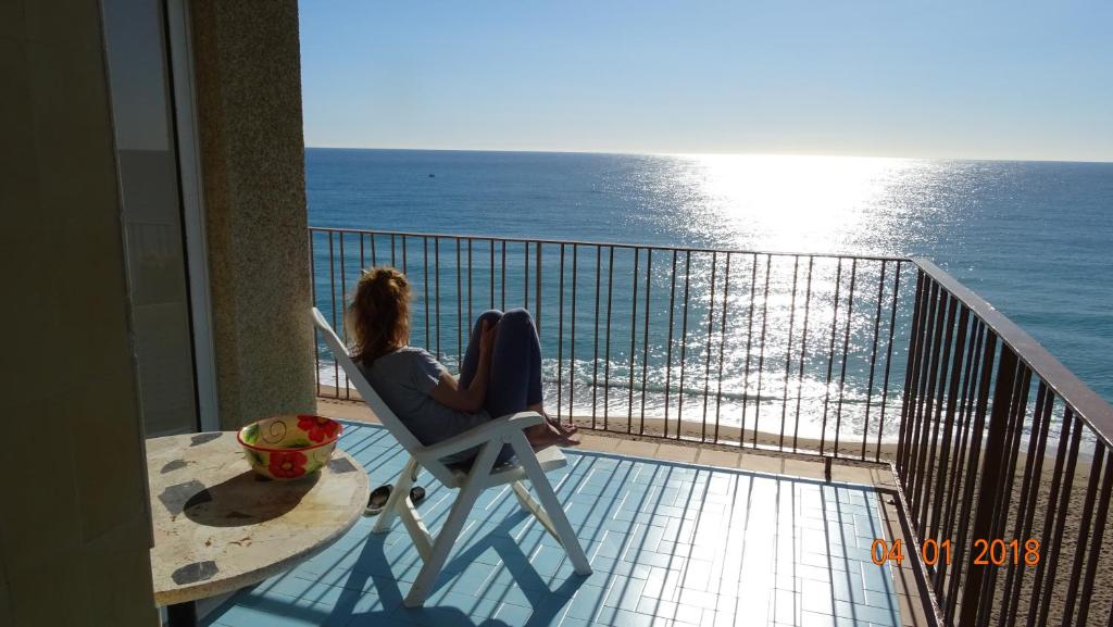 Dos mujeres sentadas en una silla en un balcón con vistas al océano en Apartament La Vista Bonica en Blanes