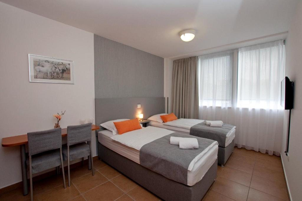 a hotel room with two beds and a table and a desk at Sobe Rooms Nataly in Sežana