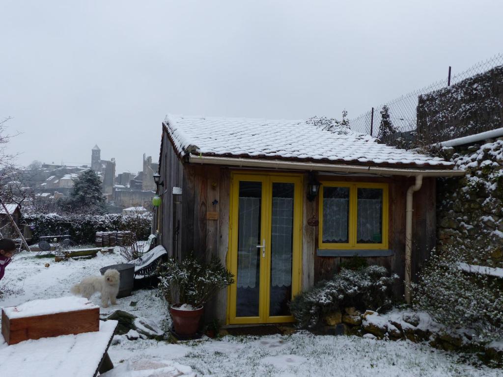 a small house with a yellow door in the snow at La Maison Rouge in Chauvigny
