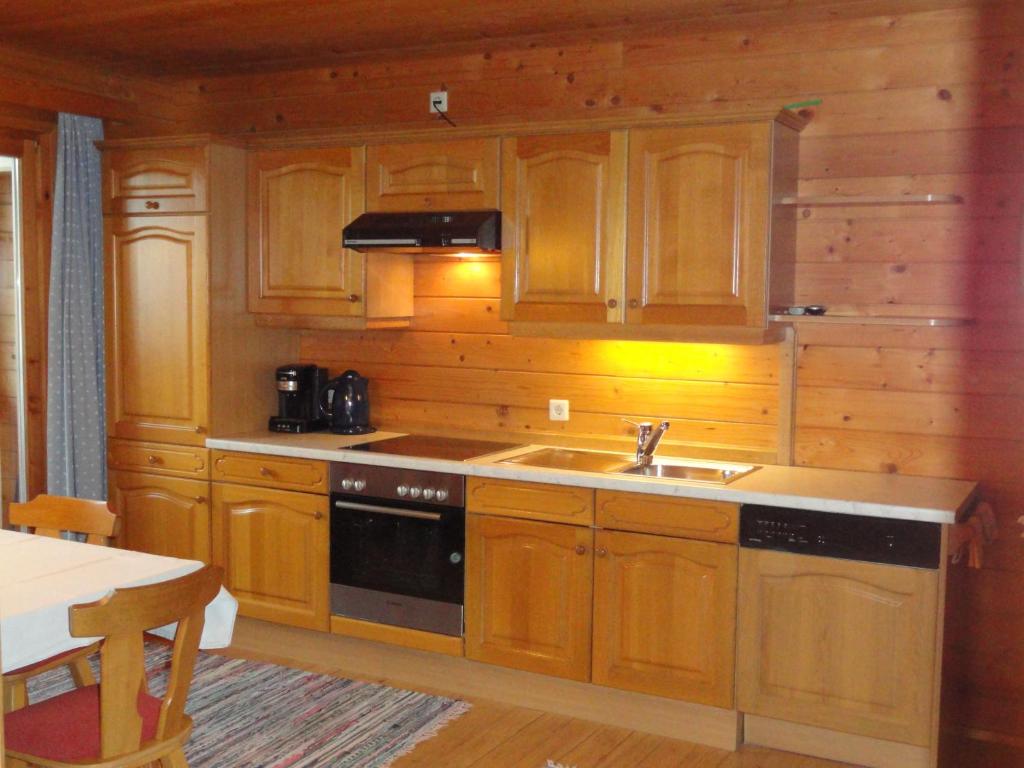 a kitchen with wooden cabinets and a sink and a stove at Baby- und Kinderhof Aicherbauer in Seeham