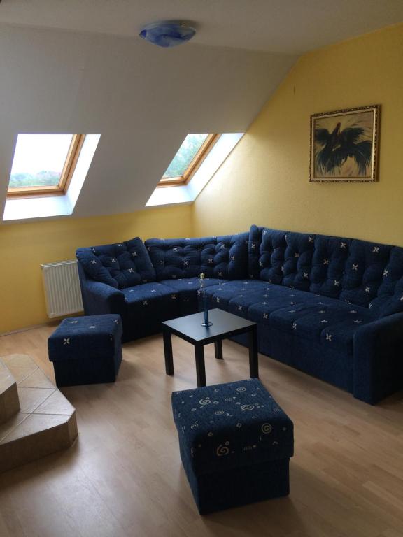 uma sala de estar com um sofá azul e uma mesa em Mary Apartment em Siófok