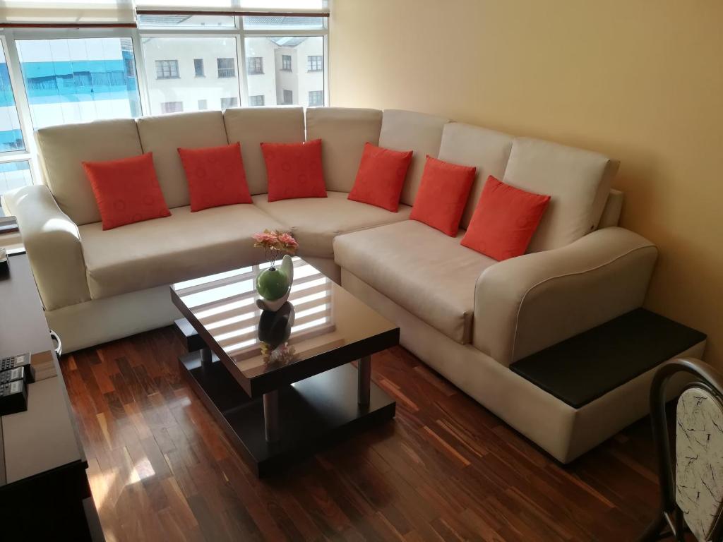 uma sala de estar com um sofá branco com almofadas vermelhas em Meraki em La Paz