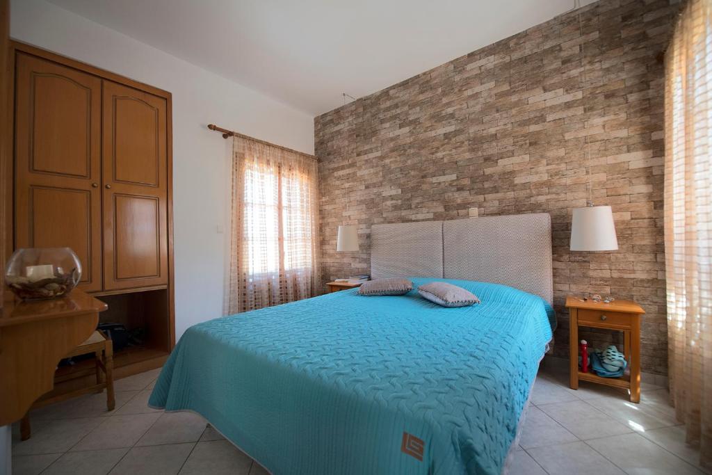 a bedroom with a blue bed and a brick wall at Amphitrite in Myrties