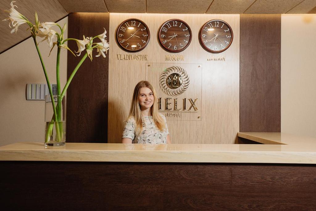 a woman standing in front of a mirror with clocks at Helix Hotel in Sochi