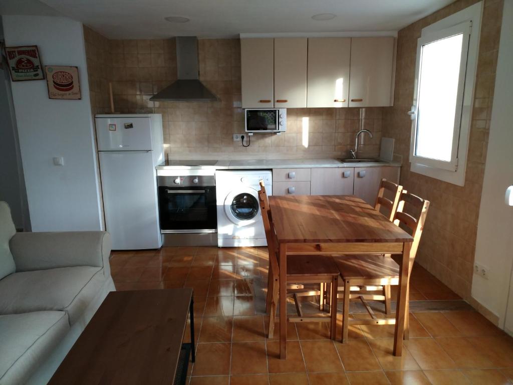 cocina con mesa de madera y cocina con nevera en Apartament LUISA, en Lloret de Mar