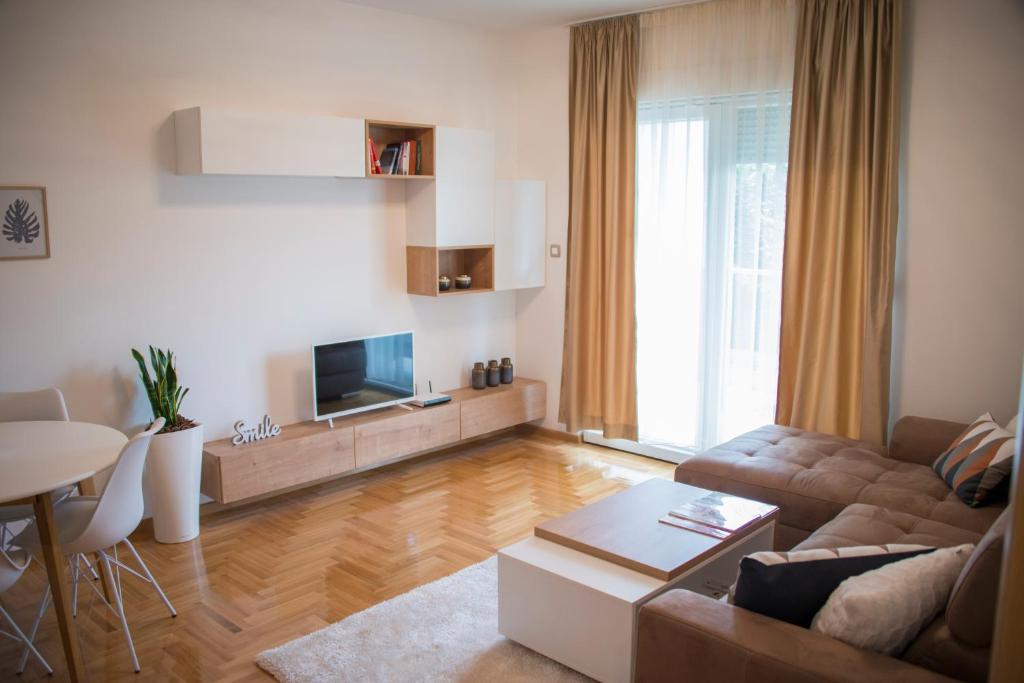 salon z kanapą, telewizorem i stołem w obiekcie Apartman Astoria w mieście Trebinje