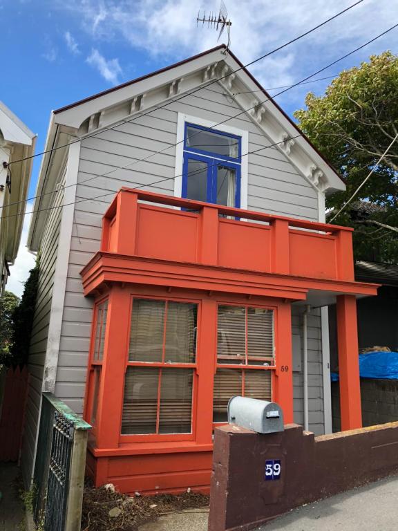 Maison orange et blanche avec fenêtre bleue dans l'établissement City Edge Nest, à Wellington