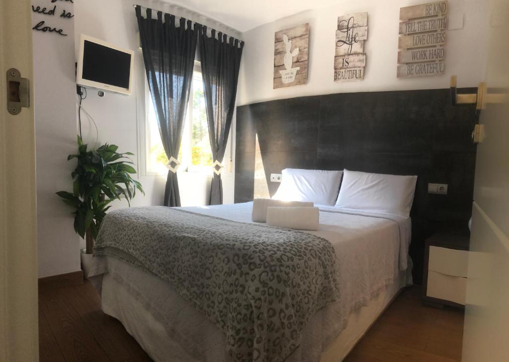 sypialnia z łóżkiem z czarnym zagłówkiem i oknem w obiekcie Luxury Playamar Beach w mieście Torremolinos