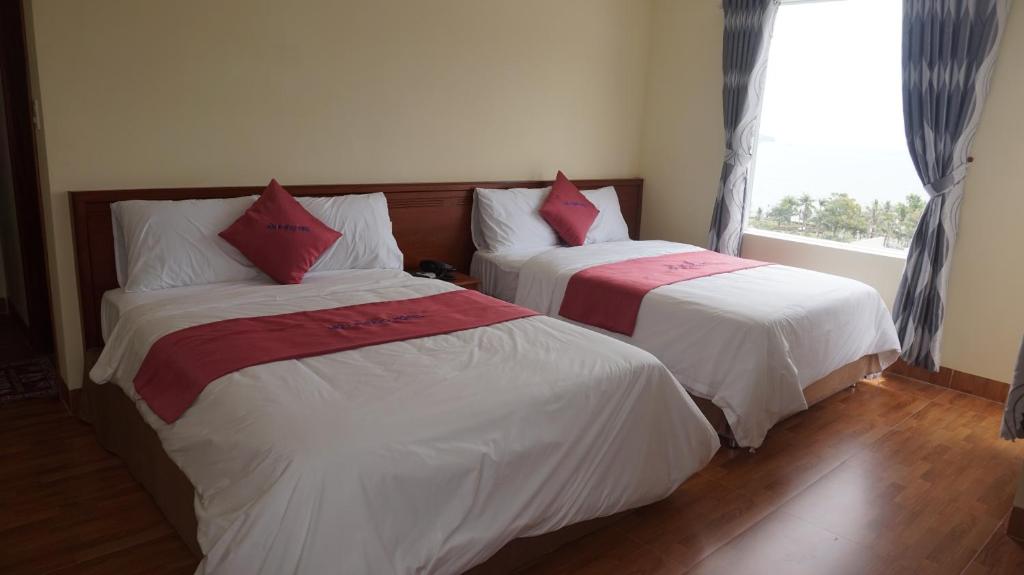 two beds in a room with a window at Khách sạn Hữu Phước in Quy Nhon