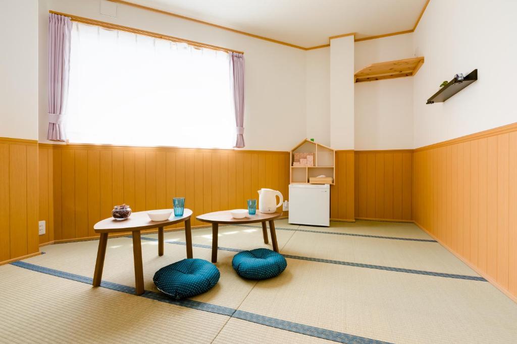 a room with two tables and a kitchen at ABC Guest House in Izumi-Sano