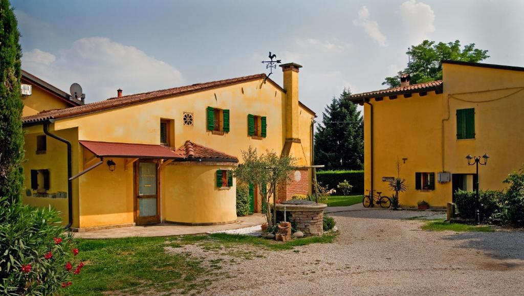 duży żółty budynek z zielonymi okiennicami w obiekcie La Brenta Vecchia w mieście Vigodarzere
