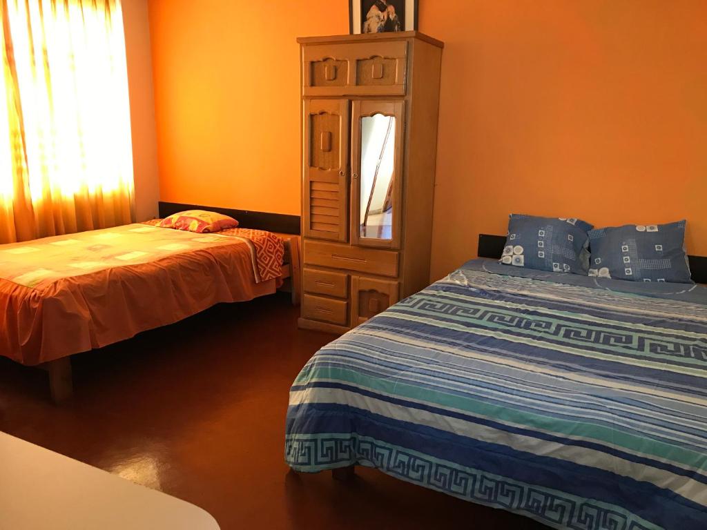 ワンカヨにあるTour Hostal Wankaのベッドルーム1室(ベッド2台、ドレッサー、鏡付)