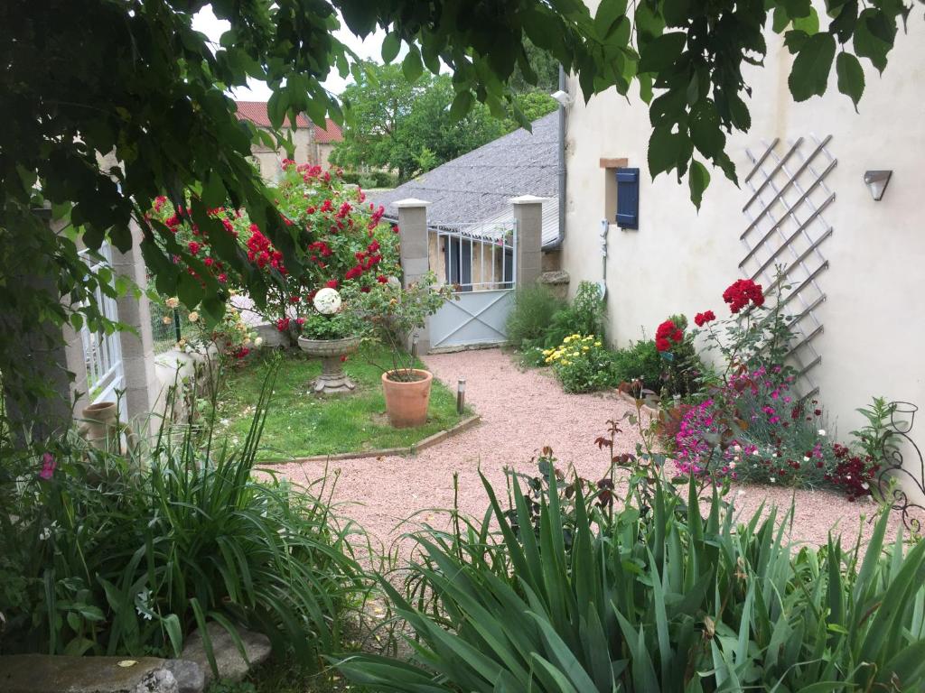 a garden with flowers and a white house at La Maison aux Hortensias in Verneuil-en-Bourbonnais