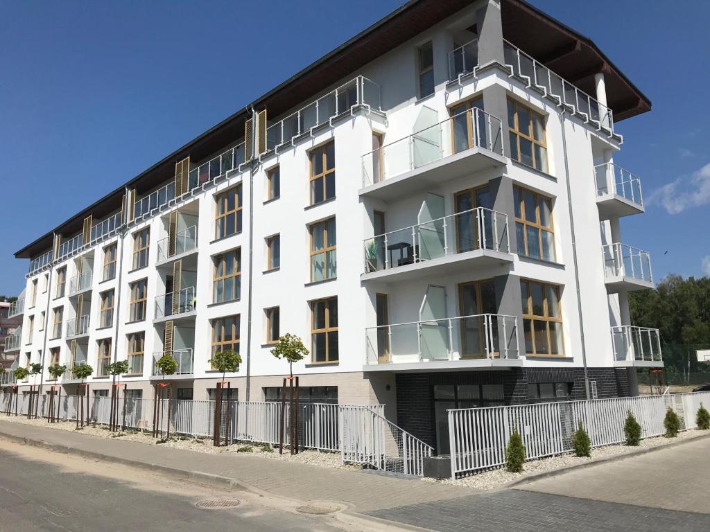 biały budynek z balkonami przy ulicy w obiekcie Porta Mare Apartamenty Słoneczne Tarasy w Dziwnówku