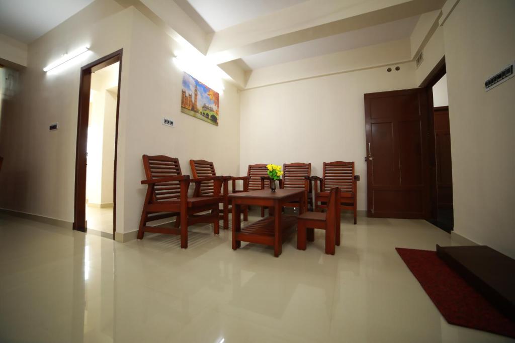 a dining room with a wooden table and chairs at Indeevaram Residency in Trivandrum