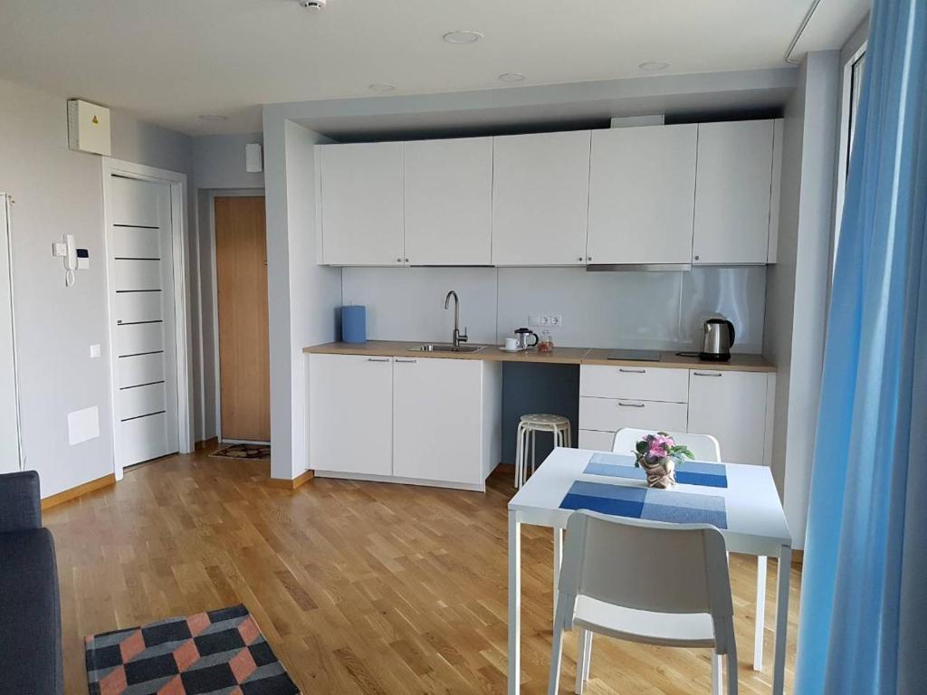 eine Küche mit weißen Schränken sowie einem Tisch und Stühlen in der Unterkunft Apartamentai Elija Plus in Šventoji