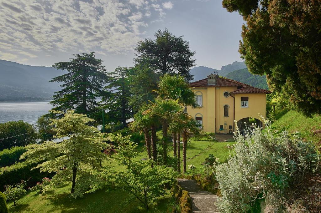 une maison jaune sur une colline avec des arbres et de l'eau dans l'établissement Villa Ucci Luxury B&B, à Onno