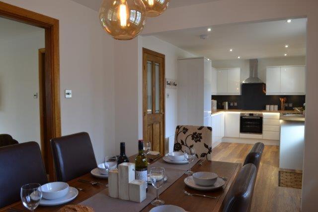 a dining room with a table and chairs and a kitchen at Beach View in Nairn