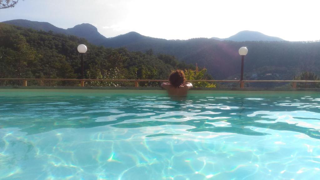 カザルツァ・リーグレにあるNonno Paco Vacanze Resortの山を背景にしたスイミングプールの女