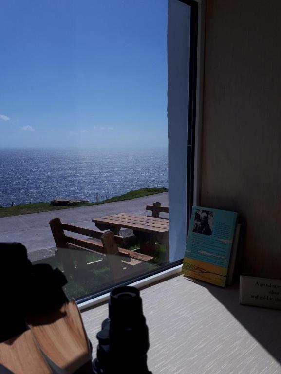 a person taking a picture of the ocean from a window at Old Irish farmhouse in Dingle