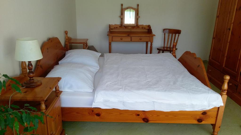 a bedroom with a wooden bed with white sheets and a table at Zelený Apartment in Růžová