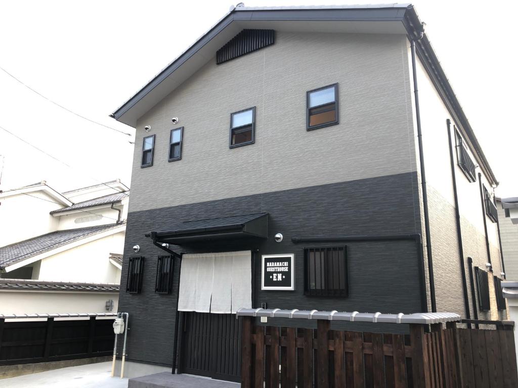 een zwart-wit gebouw met een hek bij Guest House En in Nara