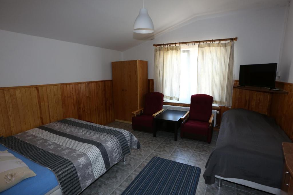 una camera con un letto e due sedie e una televisione di VillaDudek a Niechorze