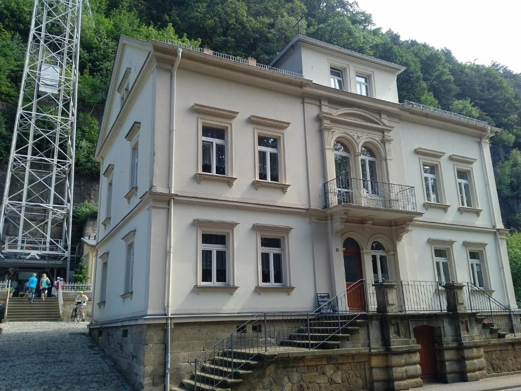 a large white building with stairs in front of a mountain at Fewo am Personenaufzug in Bad Schandau