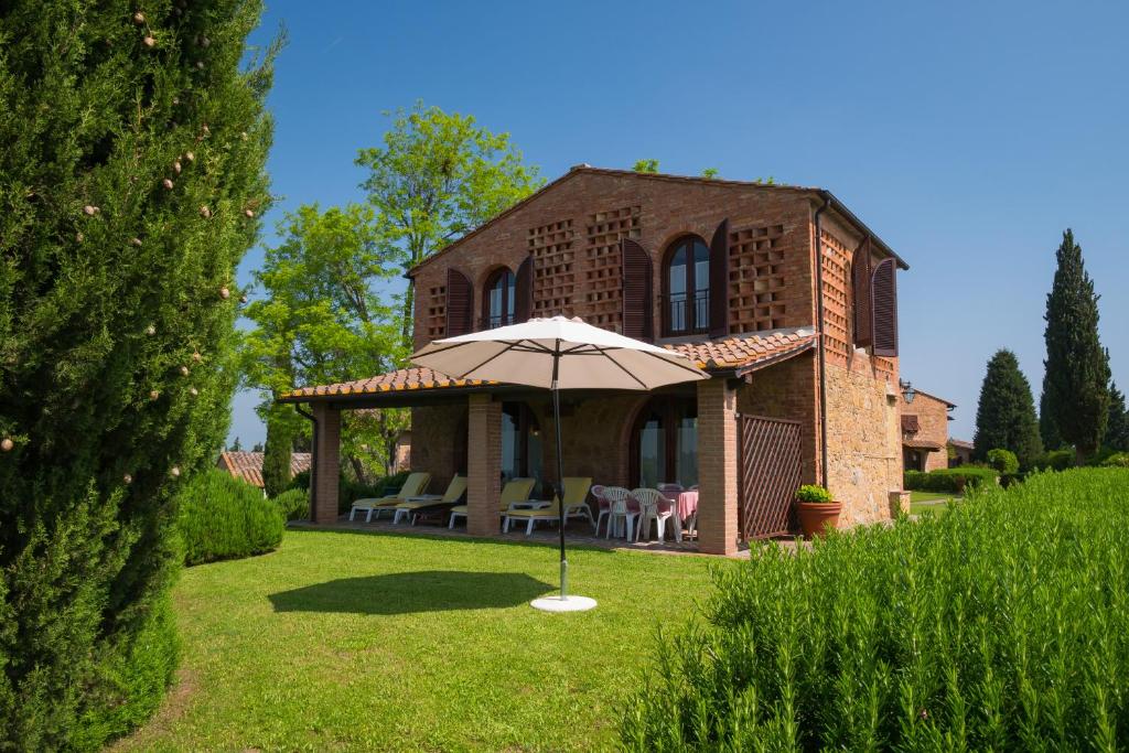 a brick house with an umbrella in the yard at Pian della Casa in Montaione