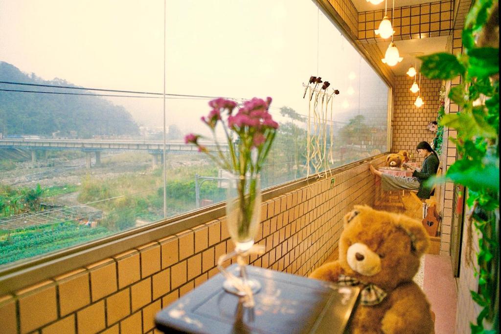 een teddybeer op een tafel met een vaas vol bloemen bij Lisin Village Homestay in Nanzhuang