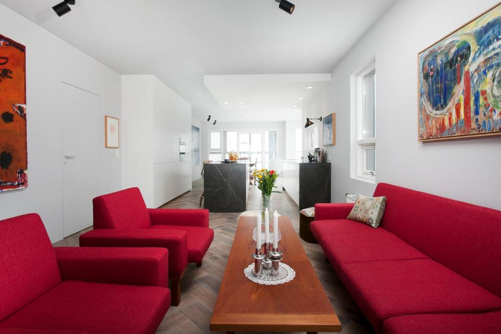 uma sala de estar com cadeiras vermelhas e uma mesa em Ocean View Luxury Apartment in Central Reykjavik em Reykjavík
