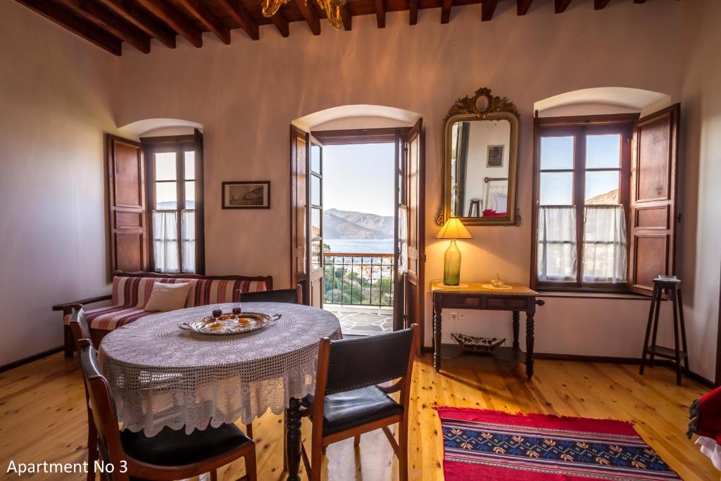 a living room with a table and chairs and windows at Villa Bella Leros in Agia Marina