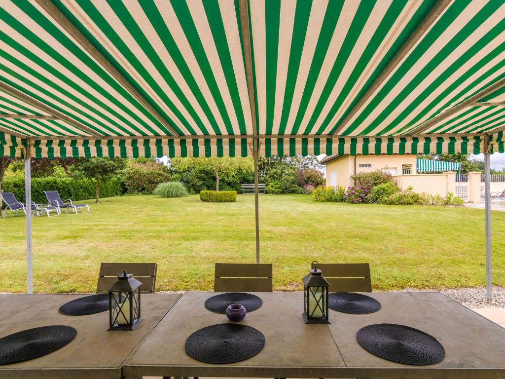 a wooden table with chairs and a large umbrella at Two comfortable houses with swimming pool near Monbazillac and Bergerac in Saint-Nexans