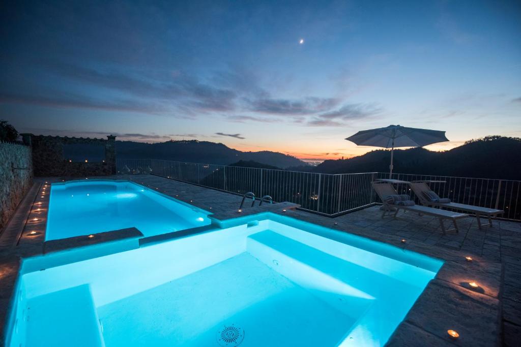 a swimming pool at night with a view of the mountains at Charming farmhouse in the hills, private pool, sea view, dream panorama in Camaiore