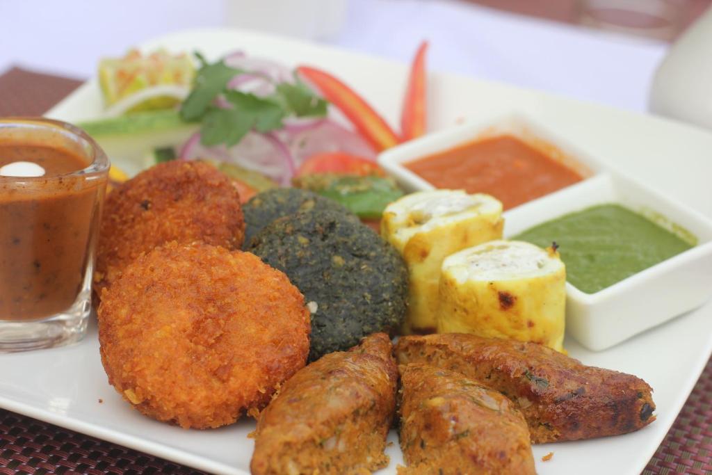 a plate of food with meat and vegetables and sauce at Hotel Surya, Kaiser Palace in Varanasi