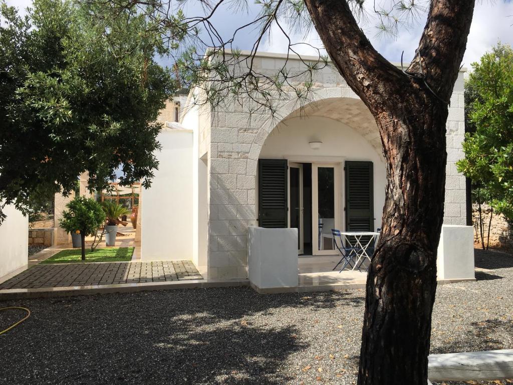 a white building with an archway next to a tree at Lamia Bianca in Locorotondo