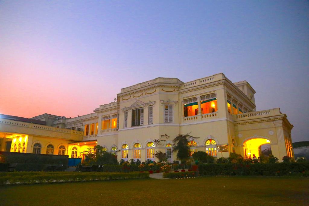 a large white building with a sunset in the background at Hotel Surya, Kaiser Palace in Varanasi