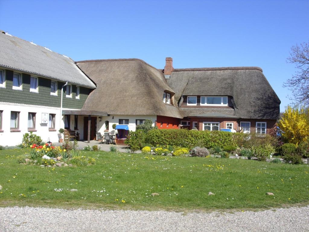 ein Haus mit einem Strohdach und einem Hof in der Unterkunft Hotel garni Zur Post in Utersum