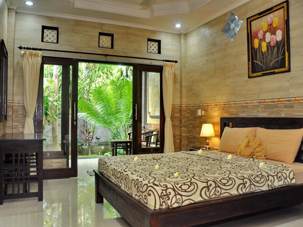 a bedroom with a large bed and a large window at Pancer House in Ubud