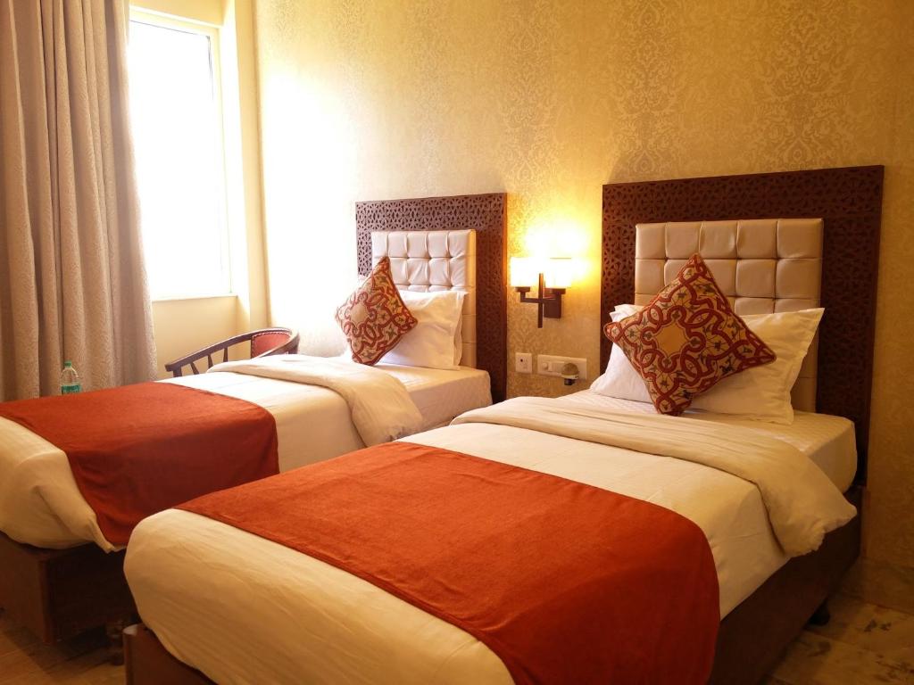 a hotel room with two beds and a window at Hotel Surya, Kaiser Palace in Varanasi
