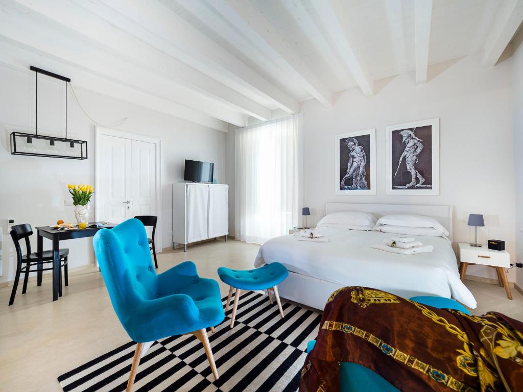 a white bedroom with a blue chair and a bed at Re Federico Boutique Hotel in Siracusa