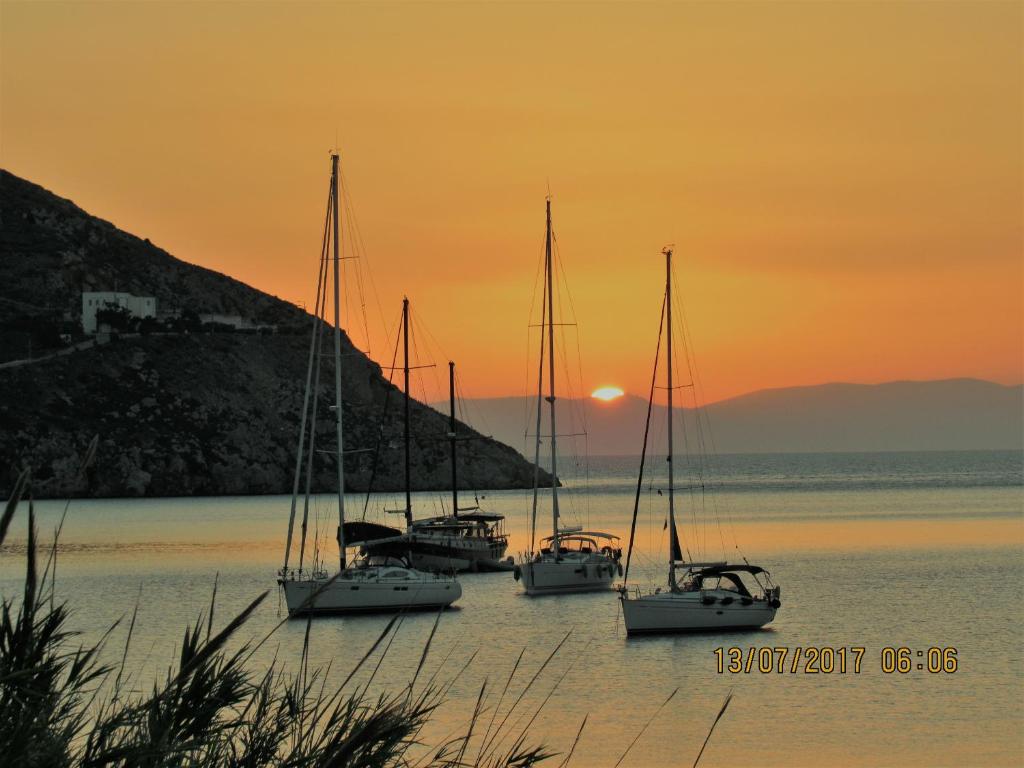 un gruppo di barche sedute in acqua al tramonto di Paradisso Studios a Vromolithos