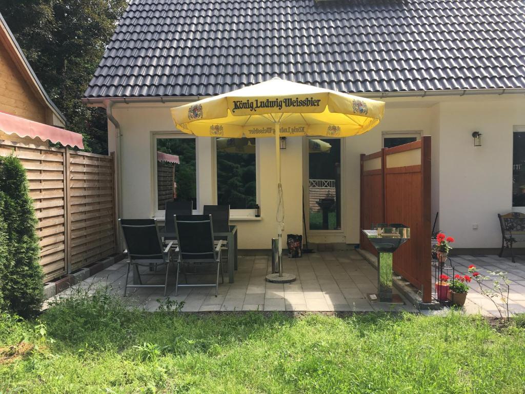 a patio with a yellow umbrella and chairs under it at Schönwalde B in Siedlung Schönwalde